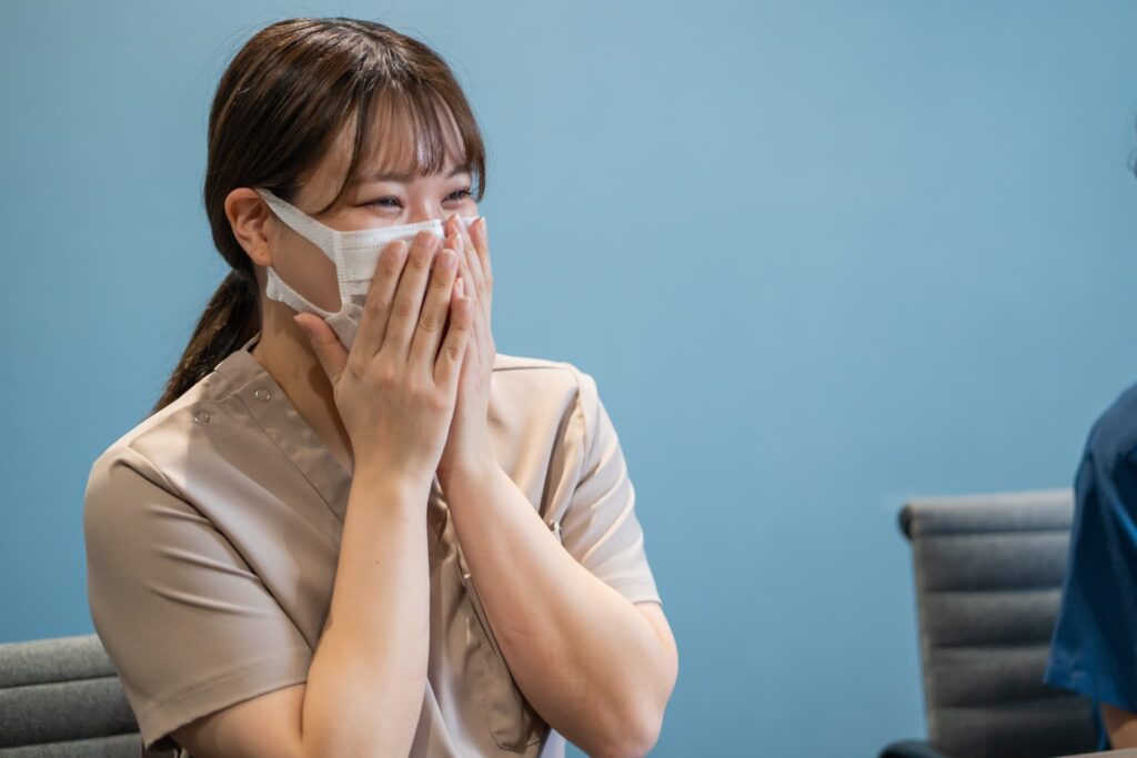 涙目で口元を抑える女性看護師