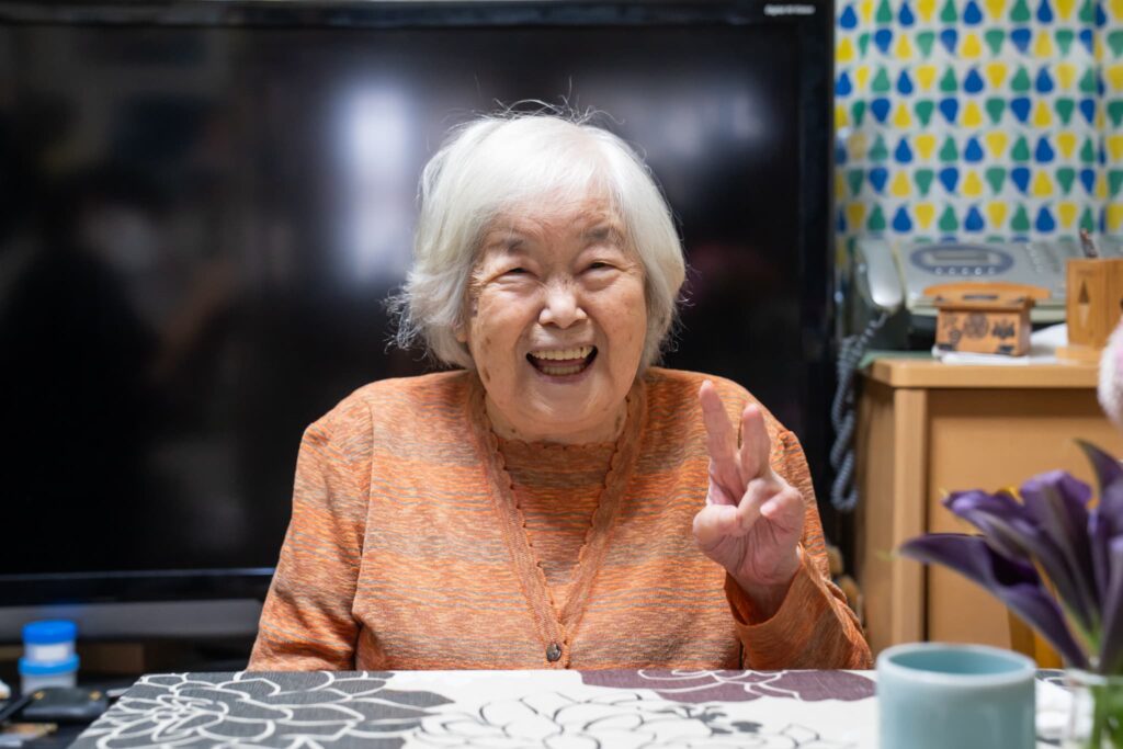 笑顔でピースサインをする高齢女性