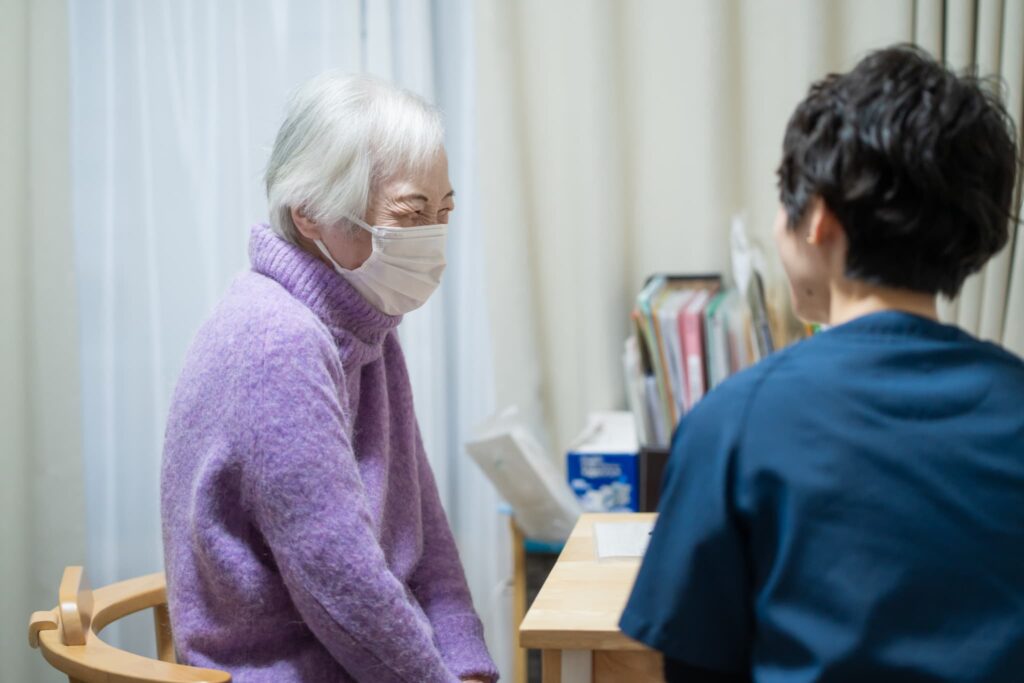 マスクをつける笑顔の女性と女医の後ろ姿
